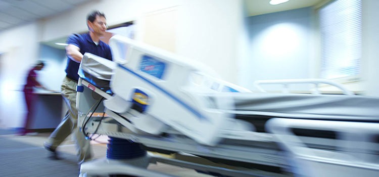 An Agiliti team member pushes a specialty bed down a hospital hallway